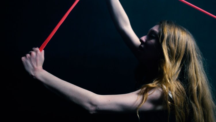 BANG! von Glossy Pain und Ensemble | © Sebastian Pircher Riah Knight zieht an einem roten Gummiband. | © Sebastian Pircher